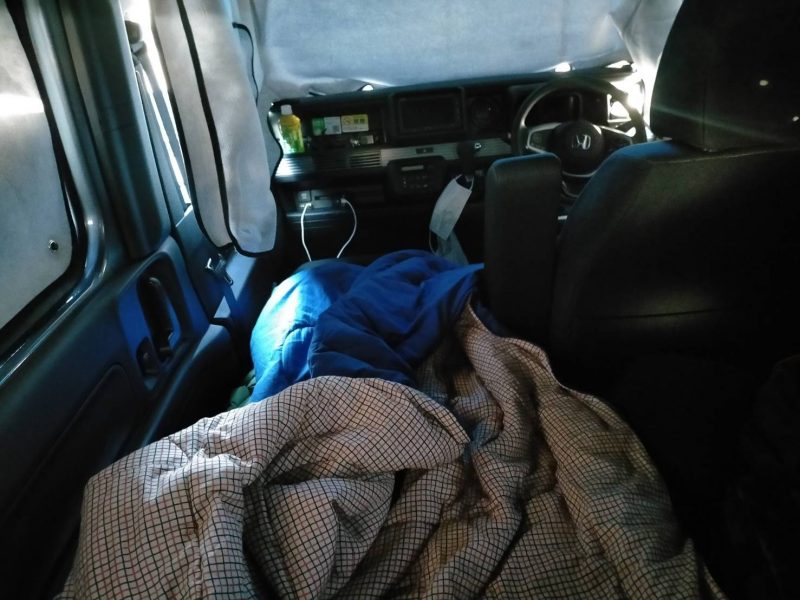 N-VANキャンピングで寝袋を使用して車中泊している写真
